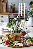 Gedeckter Tisch mit Vorspeisenplatte, Brot und Kerzen