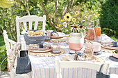 Sommerlich gedeckter Tisch im Garten mit Blumenstrauß und Brotkorb