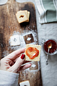 Linzer Plätzchen mit roter Beerenmarmelade in Herzfomr bestreichen