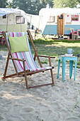 Klappstuhl mit bunt gestreiftem Stoffbezug und Beistelltisch auf Campingplatz