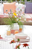 Bouquet of mixed summer flowers and candles on garden table