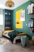 Children's room with green and yellow wall design, single bed and toy elephant