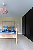 Bedroom with wooden frame bed and wardrobe with black sliding doors