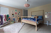 Room with wooden bed, colorful wall art and clothes rack