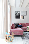 Living room with pink velvet sofa and rattan basket, floor-length curtains