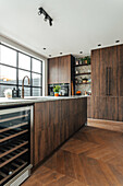 Modern kitchen with dark wooden fronts, large window and herringbone parquet flooring