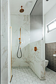 Modern bathroom with marble tiles, gold fittings and hexagonal floor tiles