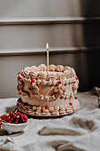 Vintage-style buttercream cake with cream ruffles, redcurrants and candle