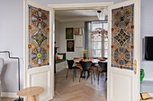 View through glazed double doors into dining room with wooden dining table and black chairs