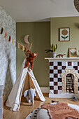 Children's room with teepee tent, elephant toy and fireplace with chequerboard tiles