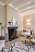 Living room with open fireplace, round mirrors and light-coloured furniture