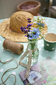 Sommerliche Tischdeko mit Lavendel und Strohhut auf gepunkteter Tischdecke