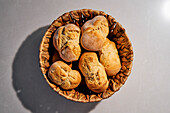 Still life view from above rustic bread rolls in brown basket\n