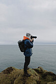 Fotograf mit Kamera auf Klippe über dem Meer, Duncansby, Schottische Highlands, Schottland