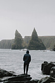 Mann schaut auf Felsformationen und Klippen an der Meeresküste, Duncansby, Schottische Highlands, Schottland