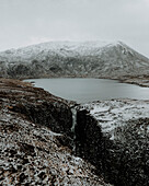 Waterfall and lake in snowy mountain landscape, Assynt, Sutherland, Scotland\n