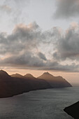 Wolken über silhouettierten Hügeln und Fluss bei Sonnenuntergang, Klakkur, Klaksvik, Färöer Inseln