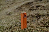Nahaufnahme orangefarbenes Wanderschild im Gras, Hvannhagi, Suduroy, Färöer Inseln