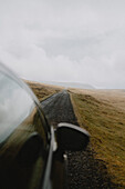 Auto fährt auf Straße in abgelegener Landschaft, Lopra, Suduroy, Färöer Inseln