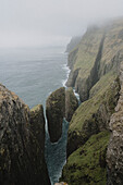 Blick auf majestätische grüne Klippen und Schornsteine über dem Meer, Dunnesdrangar, Vagar, Färöer Inseln