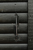 Cast iron thermometer on black wall of house\n