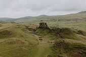 Felsformation in grasbewachsener Berglandschaft, Fairy Glen, Isle of Skye, Schottland