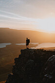 Wanderer auf einem Berg mit Blick auf einen idyllischen Sonnenuntergang, Assynt, Sutherland, Schottland