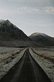 Eisige Straße unterhalb ruhiger, abgelegener Berge, Glencoe, Schottische Highlands, Schottland