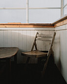 Sunlight over wooden folding chair at table below window\n