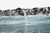 Snowmelt waterfall pouring over cliffs into ocean, Antarctic Peninsula, Weddell Sea, Antarctica\n