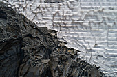 Aerial view textured rocks and protective tarpaulin over Rhone Glacier, Switzerland\n