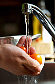 Männerhände waschen Cherrytomaten unter fließendem Wasser