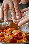 Man's hands seasoning cherry tomatoes with salt\n
