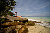 Back of young woman lying on rocks sunbathing and relaxing, Koh Phi Phi, Thailand\n
