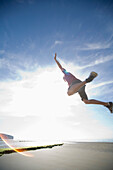 Man in mid air jump on sunny beach\n