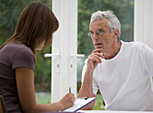 Close up of young woman taking notes from consultation with gray haired man\n