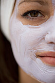 Extreme close up of young woman with mauve beauty mask\n