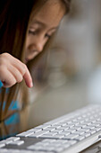 Close up of little girl hand typing on computer keyboard\n