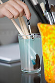 Close up of young girl hands rinsing paintbrush in water\n