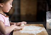 Young girl rolling dough on table\n