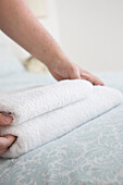 Close up of man hands adjusting towel on bed\n