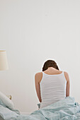 Rückenporträt einer Frau auf dem Bett sitzend