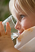 Close up of young blonde boy drinking water\n