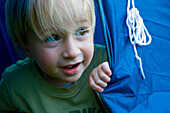 Young blonde boy playing inside a tent\n