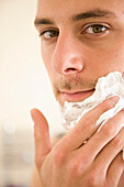 Close up of young man applying shaving cream\n
