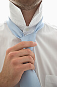 Close up  of a young man tightening his tie\n
