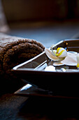 White flowers floating in square bowl with brown towels\n