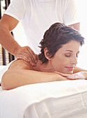 Männlicher Massagetherapeut massiert Frau an den Schultern im Freien
