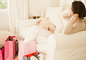 Woman sitting in living room with shopping bags\n