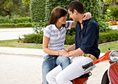 Portrait of young couple sitting on scooter embracing\n